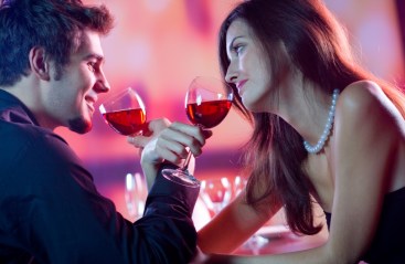 Young happy amorous couple celebrating with red wine at restaurant