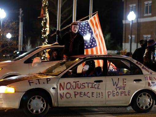 Demonstrators ride a car past the police station in